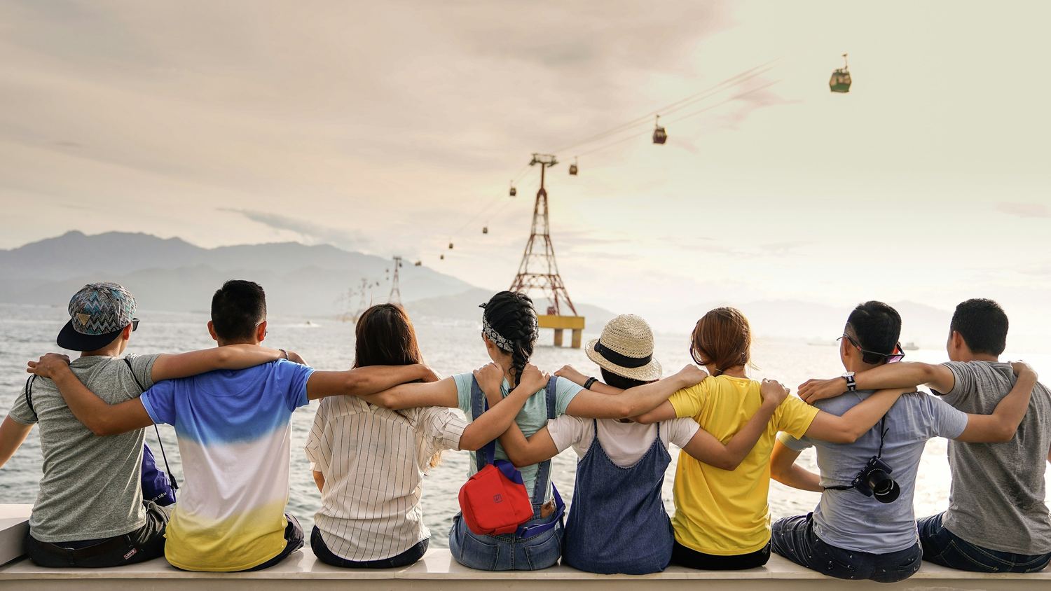 A group of people standing together with their arms around one another at dusk