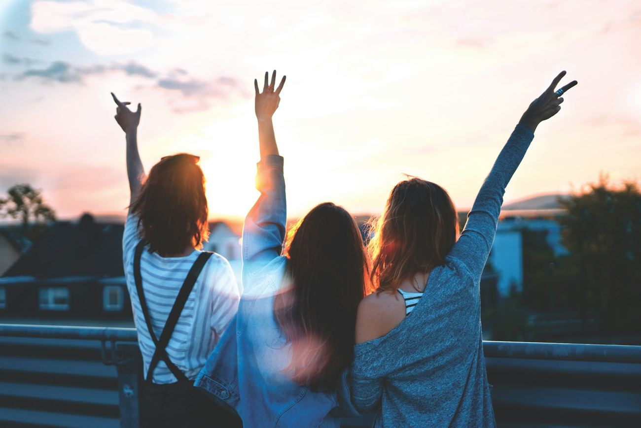 People raising their arms toward a bright sky